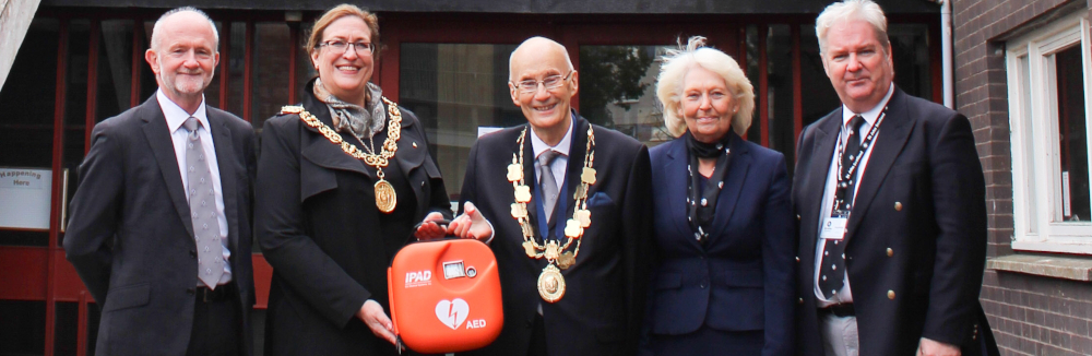 A group of people pose with a defibrillator 